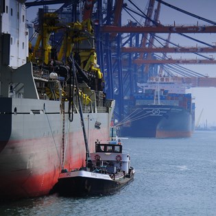A tug boat alongside a larger vessel in a harbour