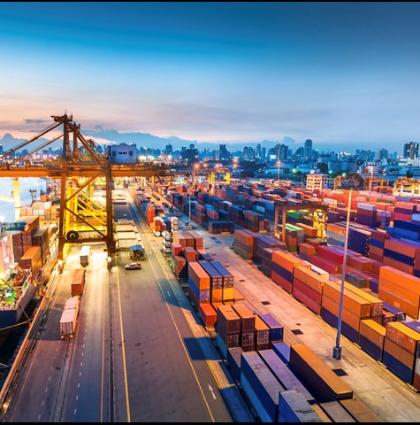 A photograph of a container port with lots of containers and a few vessels docked